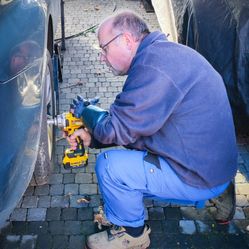 Anwender macht mit Handorthese Reifenwechsel an seinem Auto